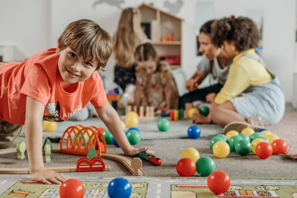 pexels-photo-8422207 Happy children and a caregiver playing with colorful toys in a lively indoor playroom setting.