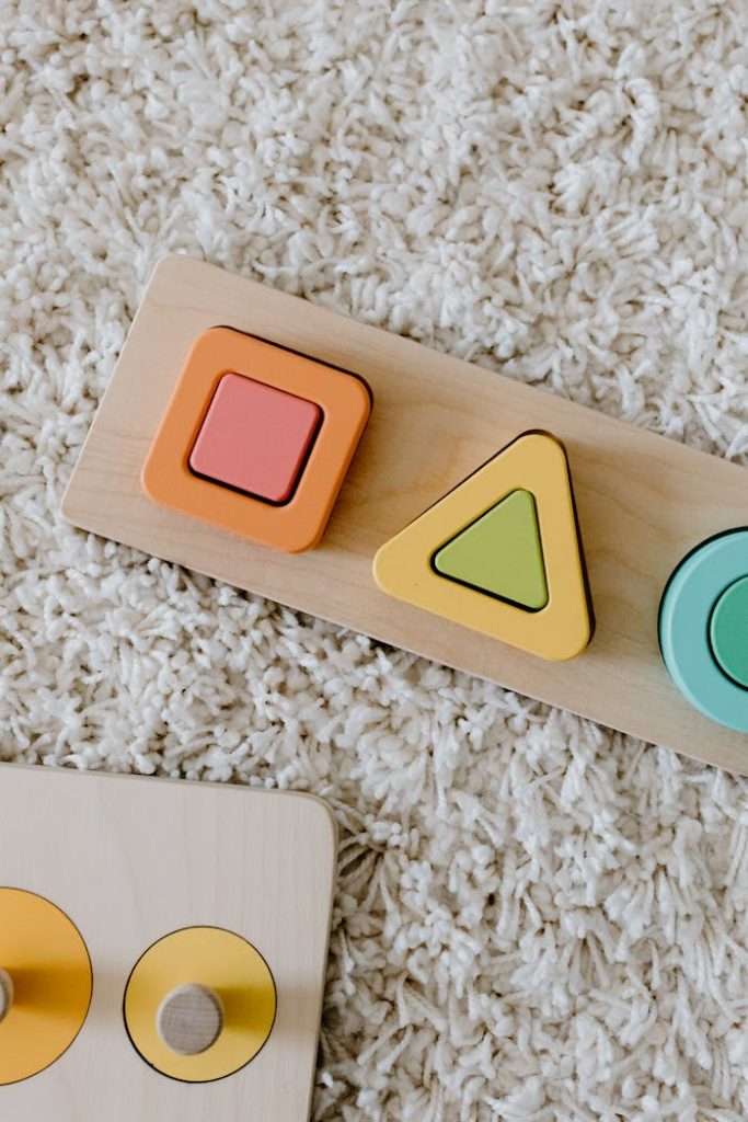 Close-up of colorful wooden educational toys on a textured carpet.